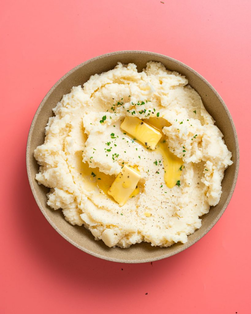 Vegan mashed potatoes without butter served in a serving dish with fresh herbs. 