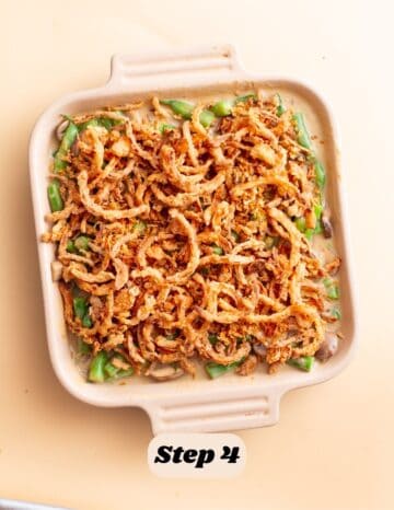 the first step in the process of making green bean casserole: the casserole is seen topped with golden brown crispy onions