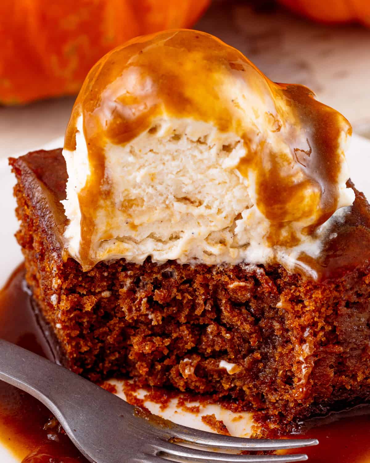 ice cream on top of vegan pumpkin sticky toffee pudding with a spoonful removed. 