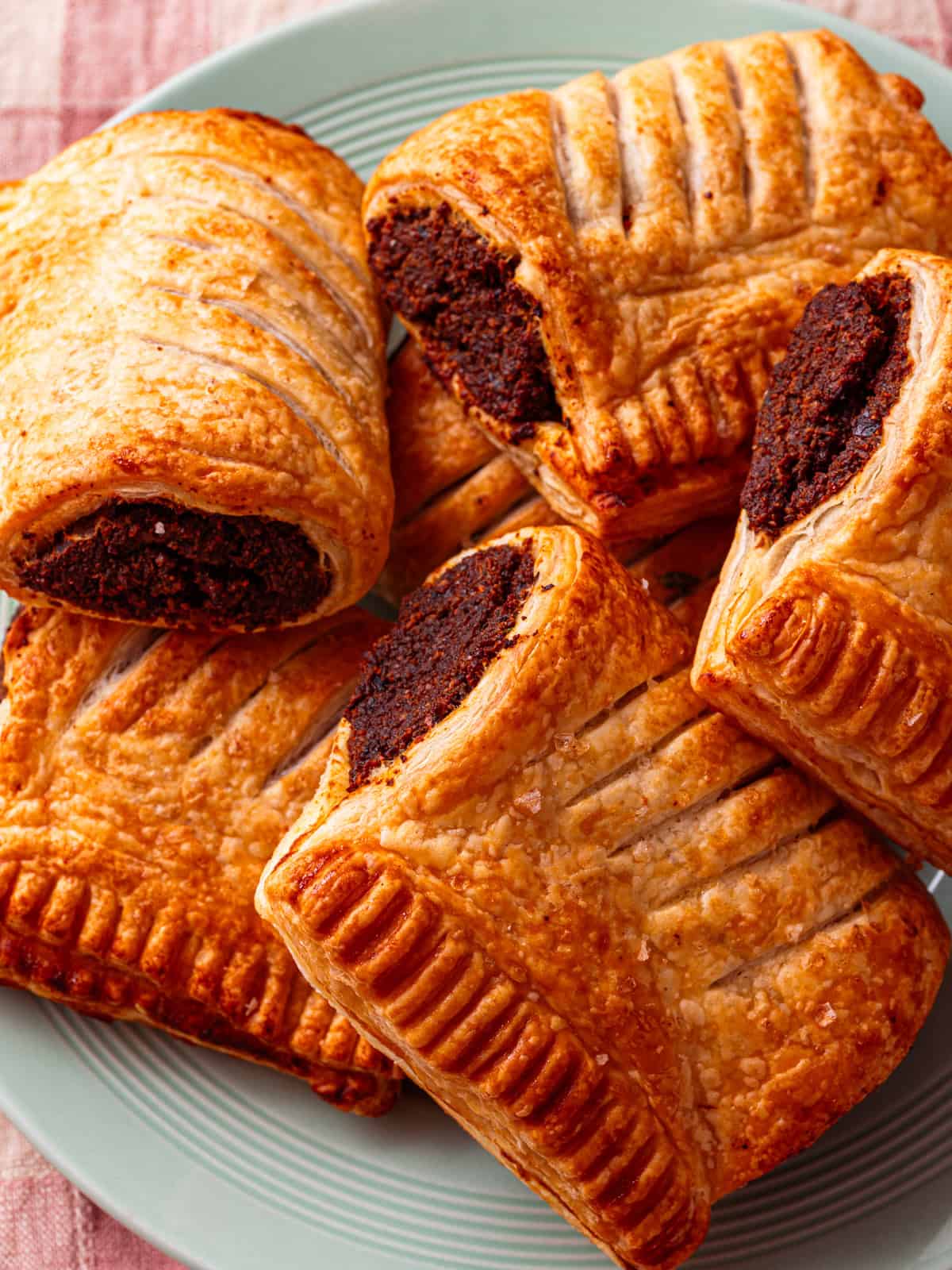 a small plate packed with vegan sausage rolls with golden brown puff pastry.