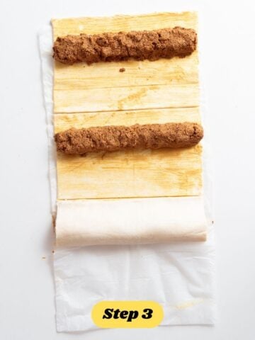 vegan sausage rolls being made. The puff pastry can be seen with mustard and filling. 