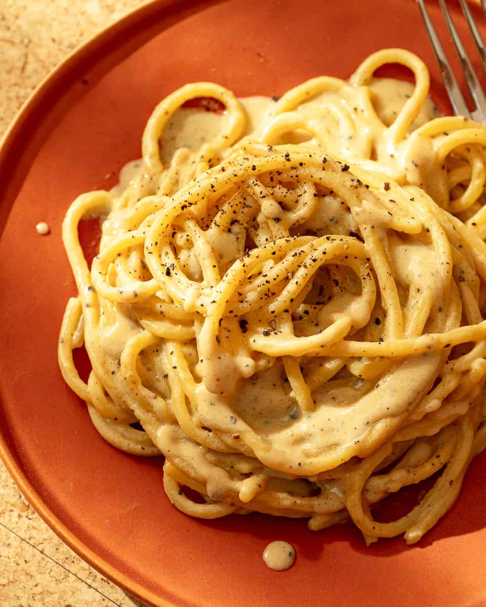 vegan cacio e pepe on an orange plate
