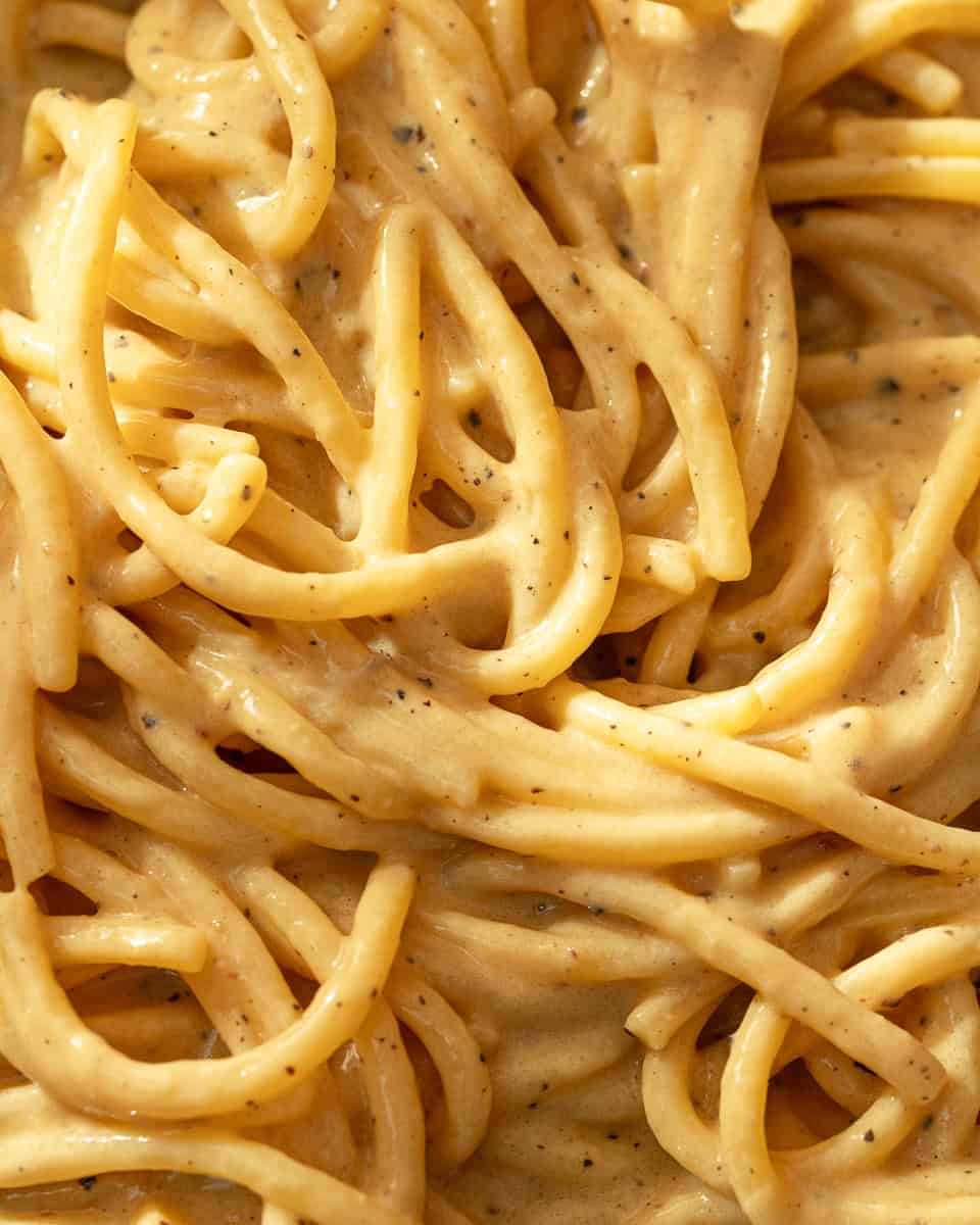 Close-up of spaghettoni coated in a creamy peppery sauce